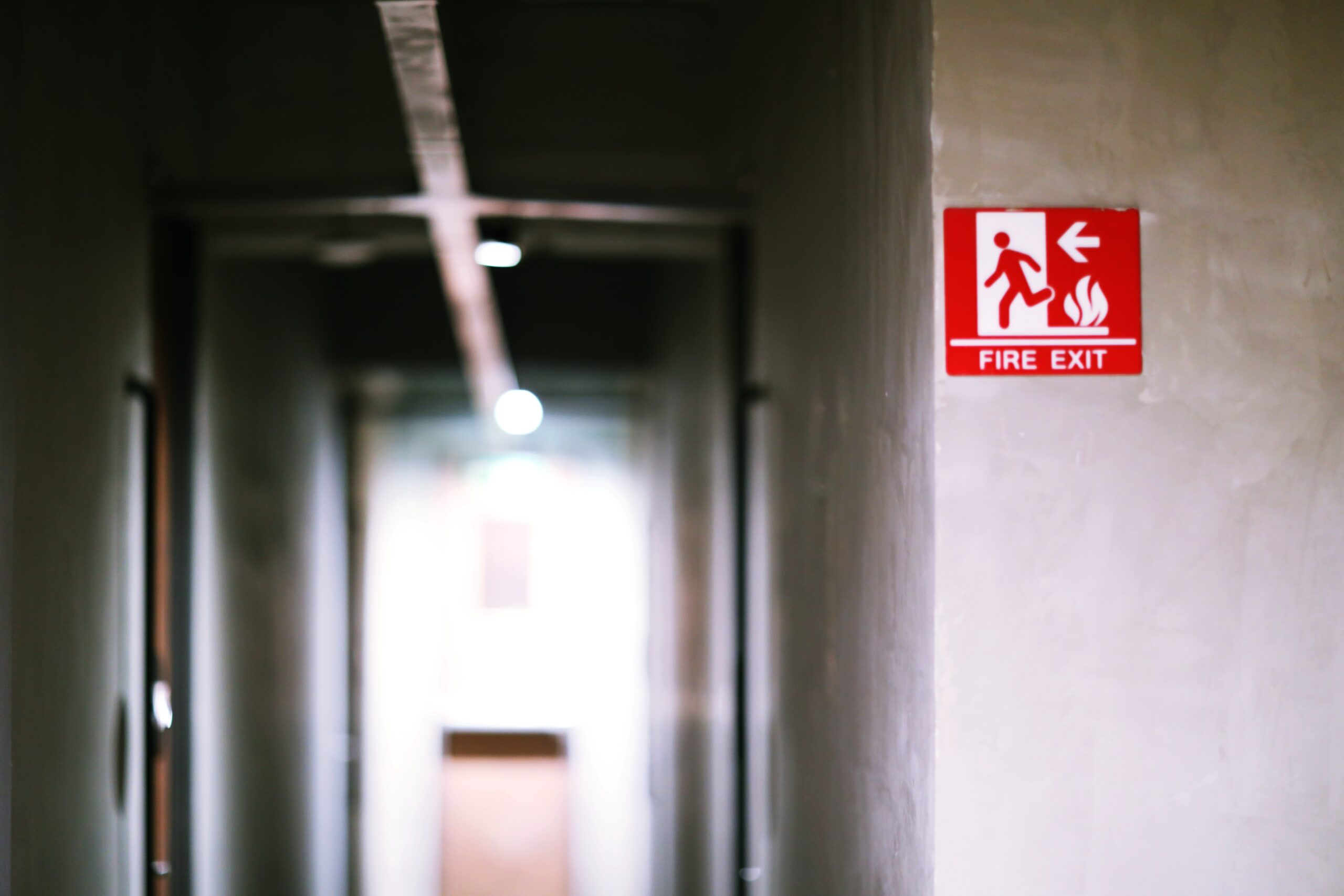 A red and white Fire Exit sign is displayed on a cement wall